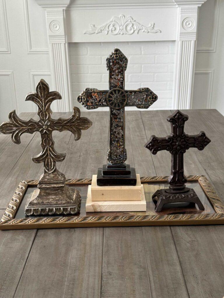 A centerpiece being made from three crosses and a picture frame. 