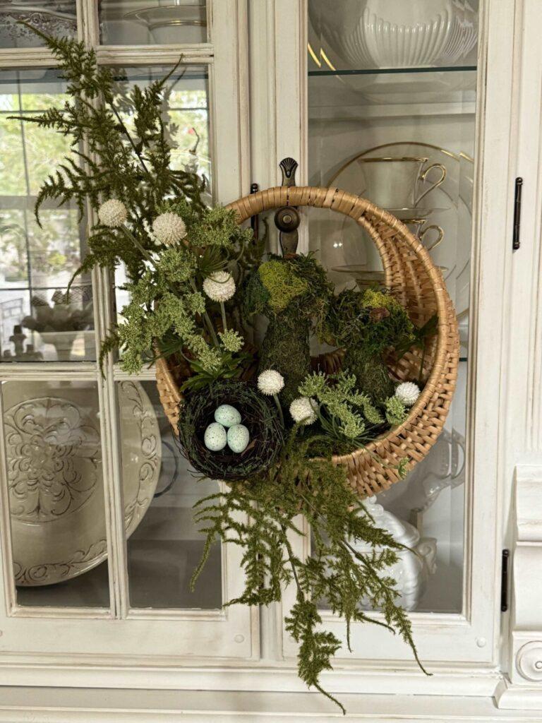 A spring basket hanging on a china cabinet. 