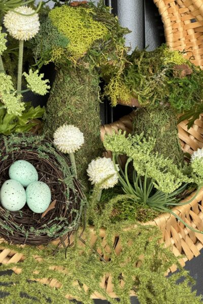 Basket wreath filled with two moss mushrooms, florals, pods, and a bird nest.