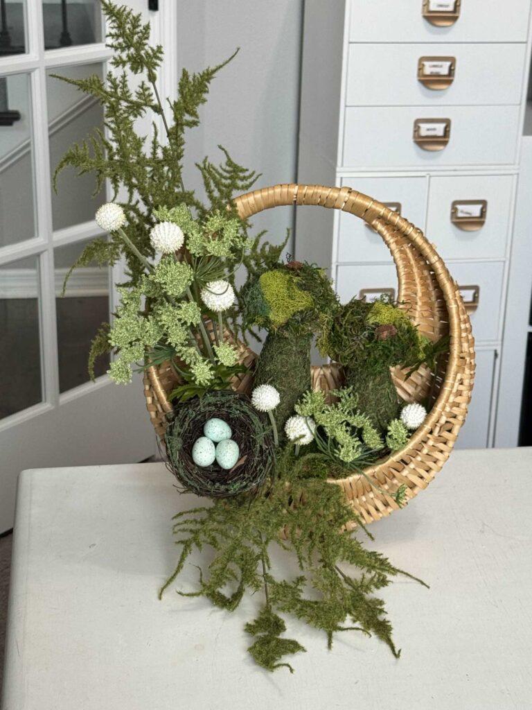 Step six to make a moss mushroom wreath is to add a bird's nest to the basket. 