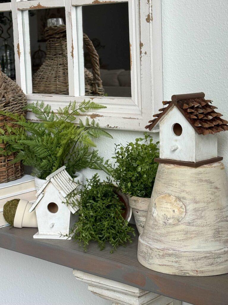 An easy Spring decor idea is to use flower pots, birdhouses, and faux plants on a shelf.