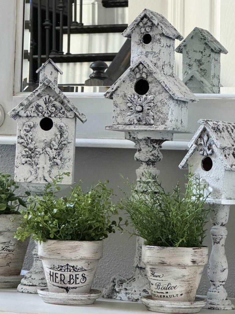 Three pedestal birdhouses and stenciled French flower pots make a pretty Spring decor idea. 