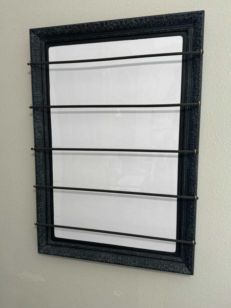 A black frame with dowel rods hanging across it. 