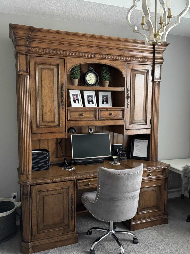 Large organized wood desk with a gray chair. 