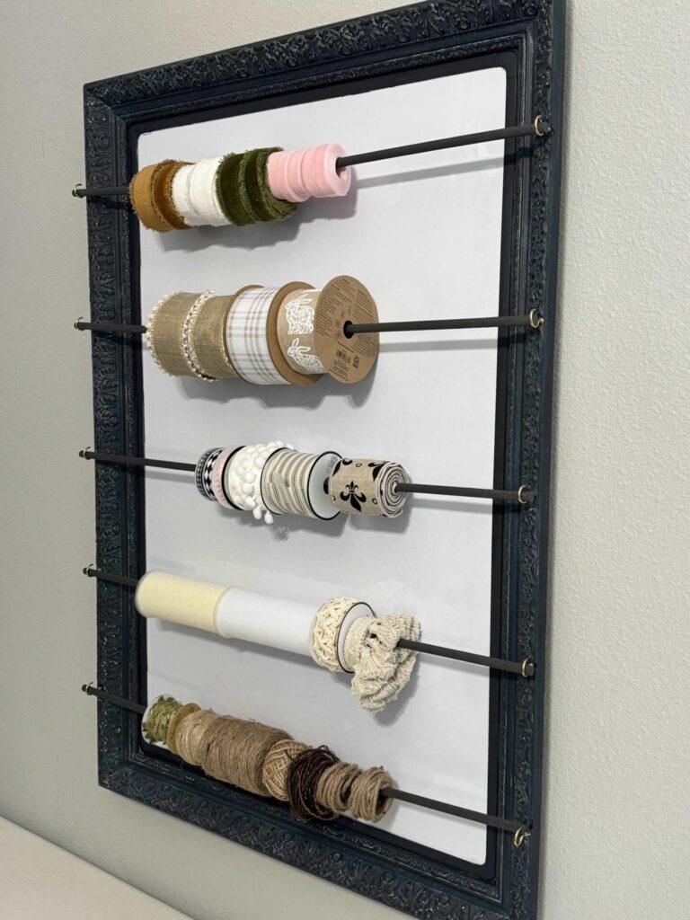 Craft room organization tip #2 is to hang ribbon from dowel rods attached to a frame. 