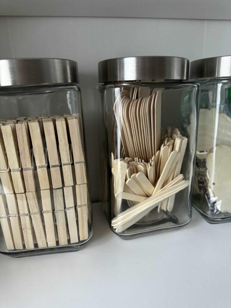 Craft room organization tip #4 is to store wood craft items in recycled cashew jars from Costco.  