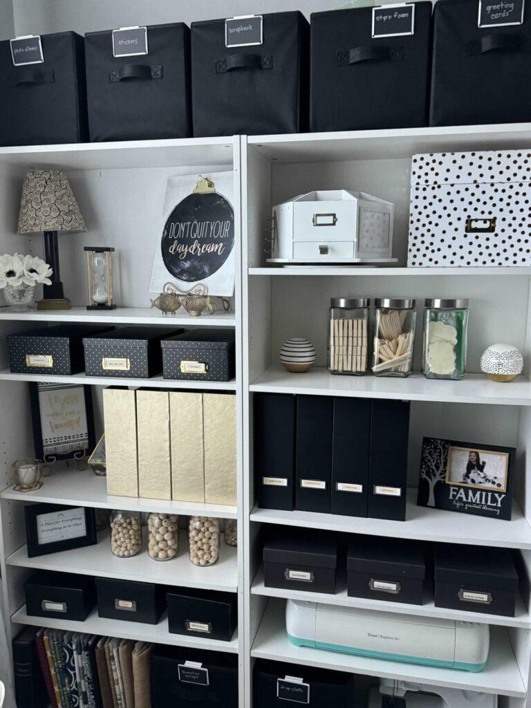 Bookshelf organized with black, gold, and white items. 