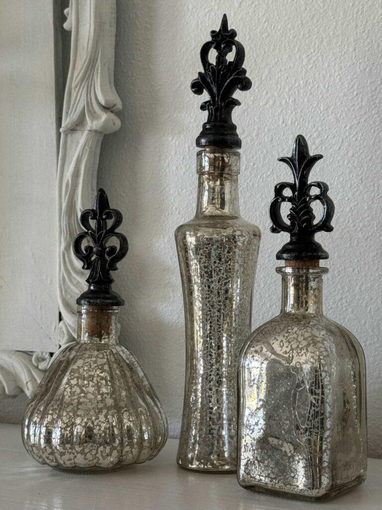 Three mercury glass decorative bottles with stoppers. 
