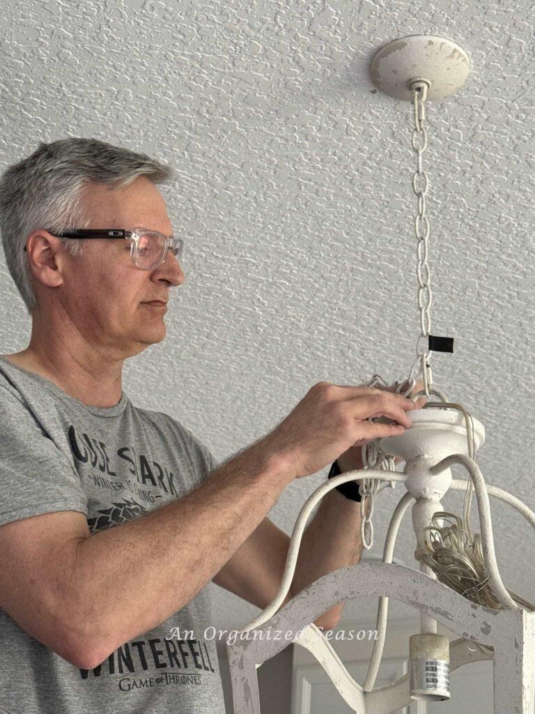 A man hanging a pendant light. 