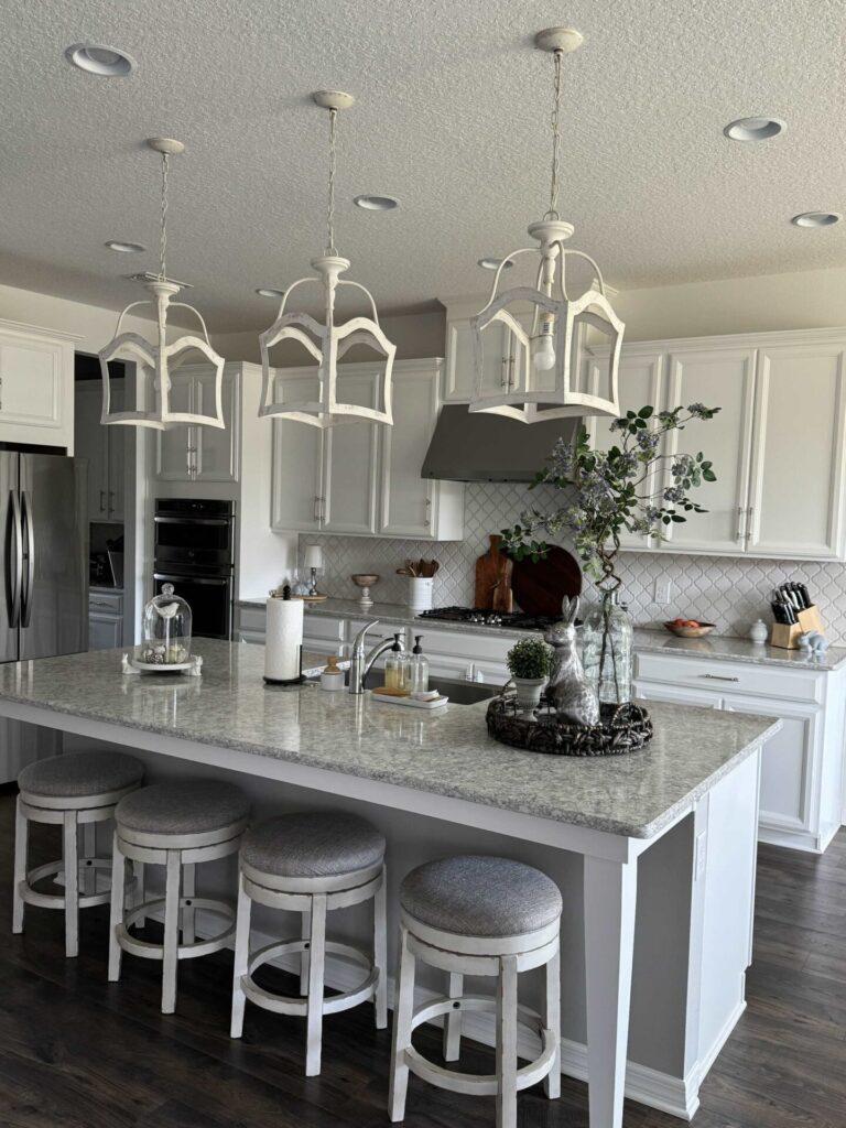 A white kitchen with three pendant lights hanging over the island. 