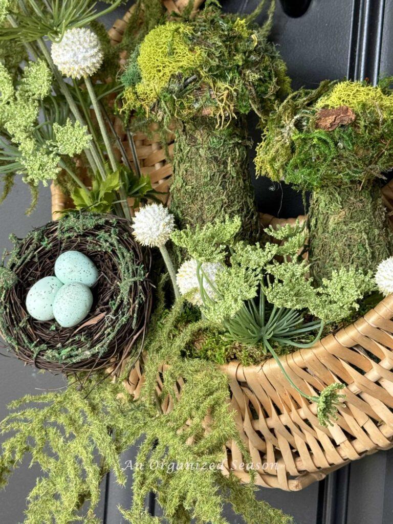 A basket filled with moss mushrooms and a bird nest hanging on a front door. 