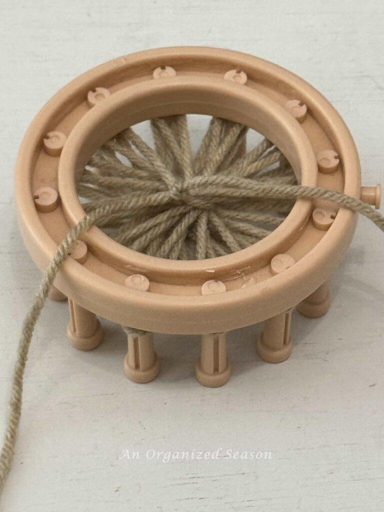 The back of a round loom with yarn tied off. 