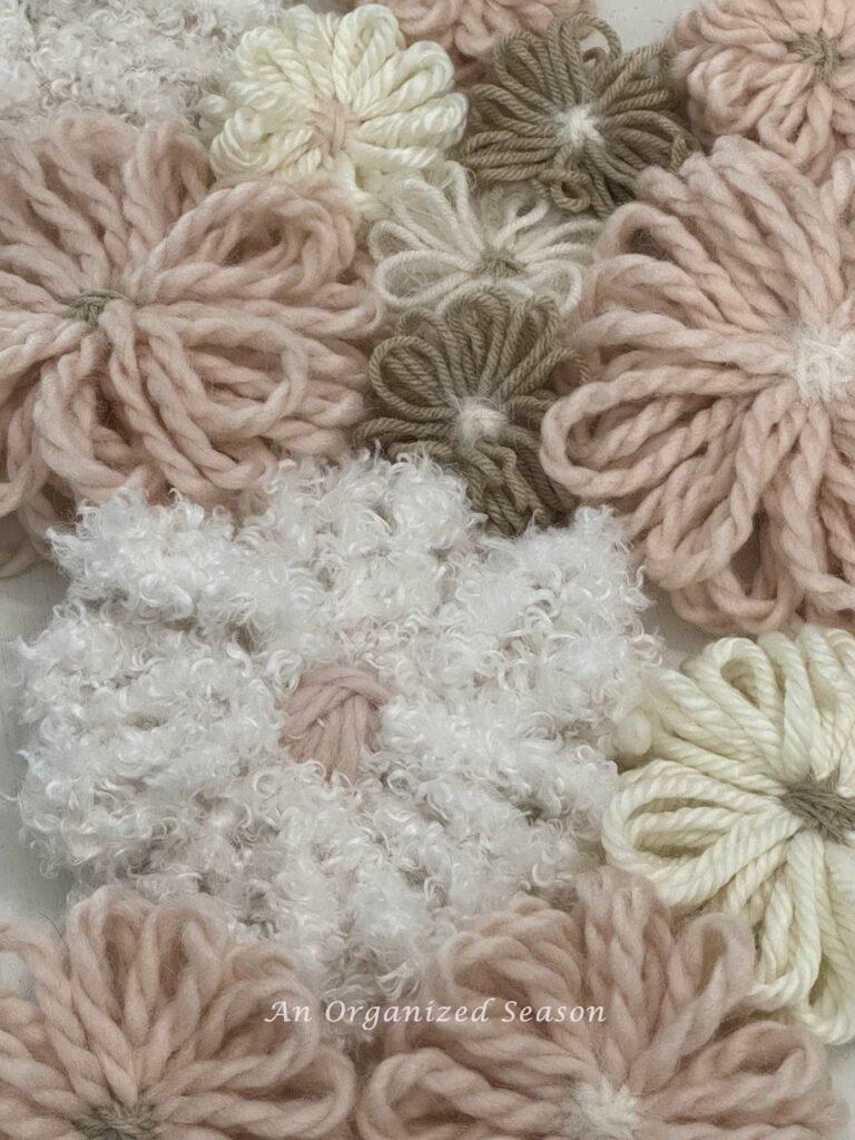 Yarn flowers in white, tan, cream, and pink. 