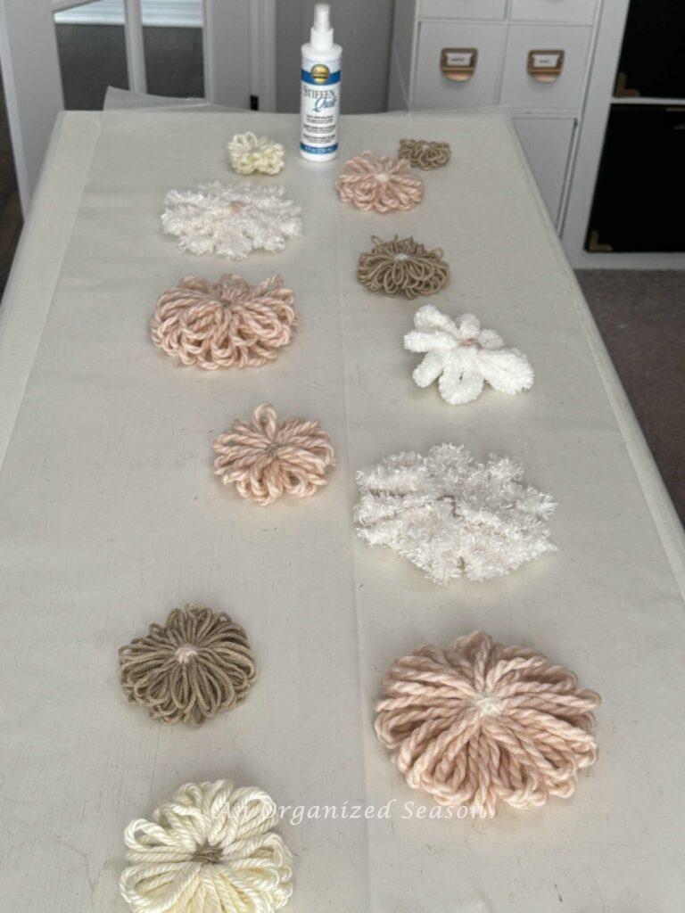 Yarn flowers on wax paper after being sprayed with stiffening spray.