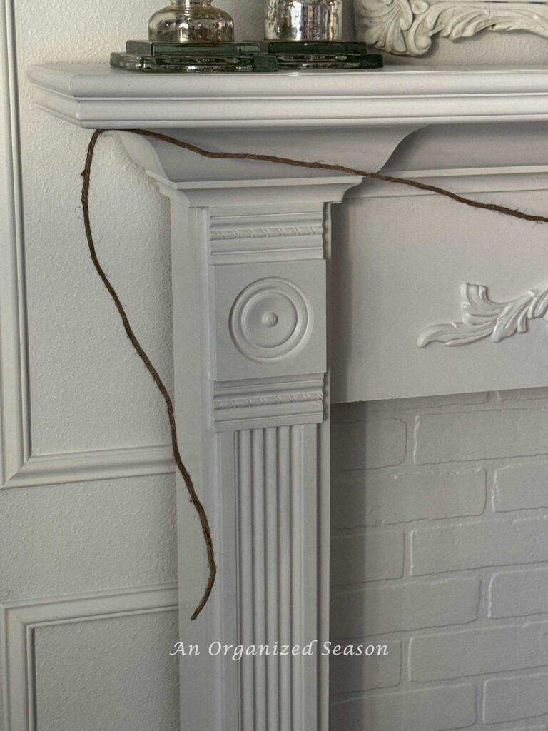 A wire covered in jute twine hanging on a mantel. 