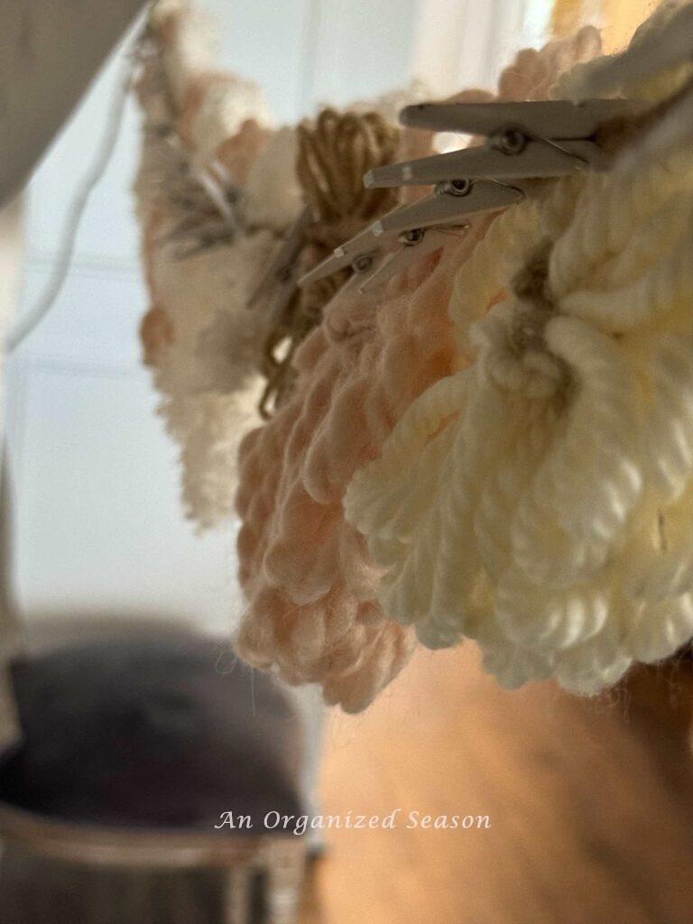 Yarn flowers attached to wire with miniature white clothes pins.