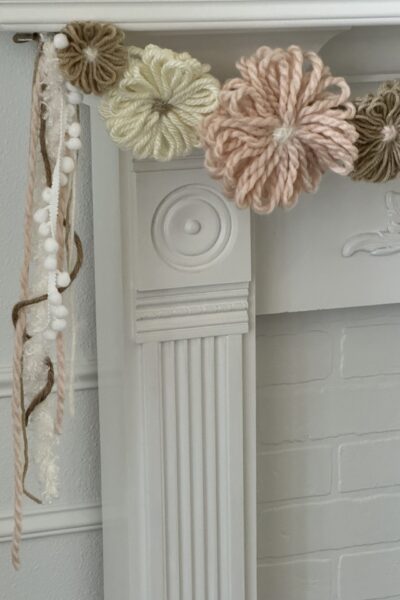 Yarn flower garland hanging on a mantel.