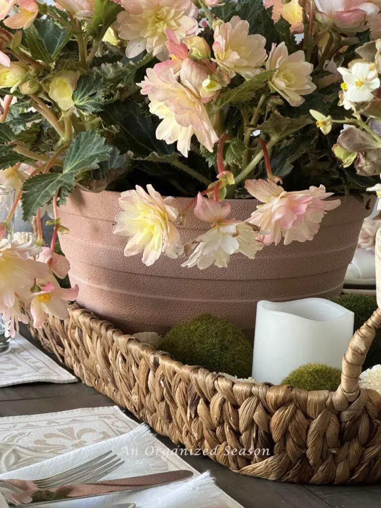 Flower pot in a basket with orbs and a candle on each end. 
