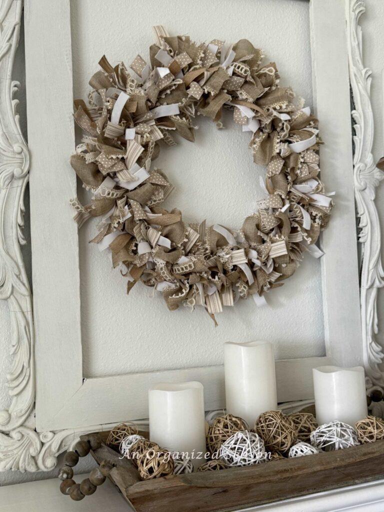 A neutral wreath hanging inside a picture frame.