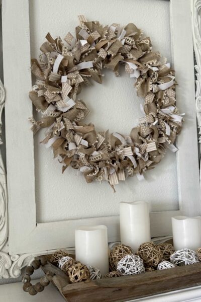 A neutral ribbon wreath hanging over a mantle.