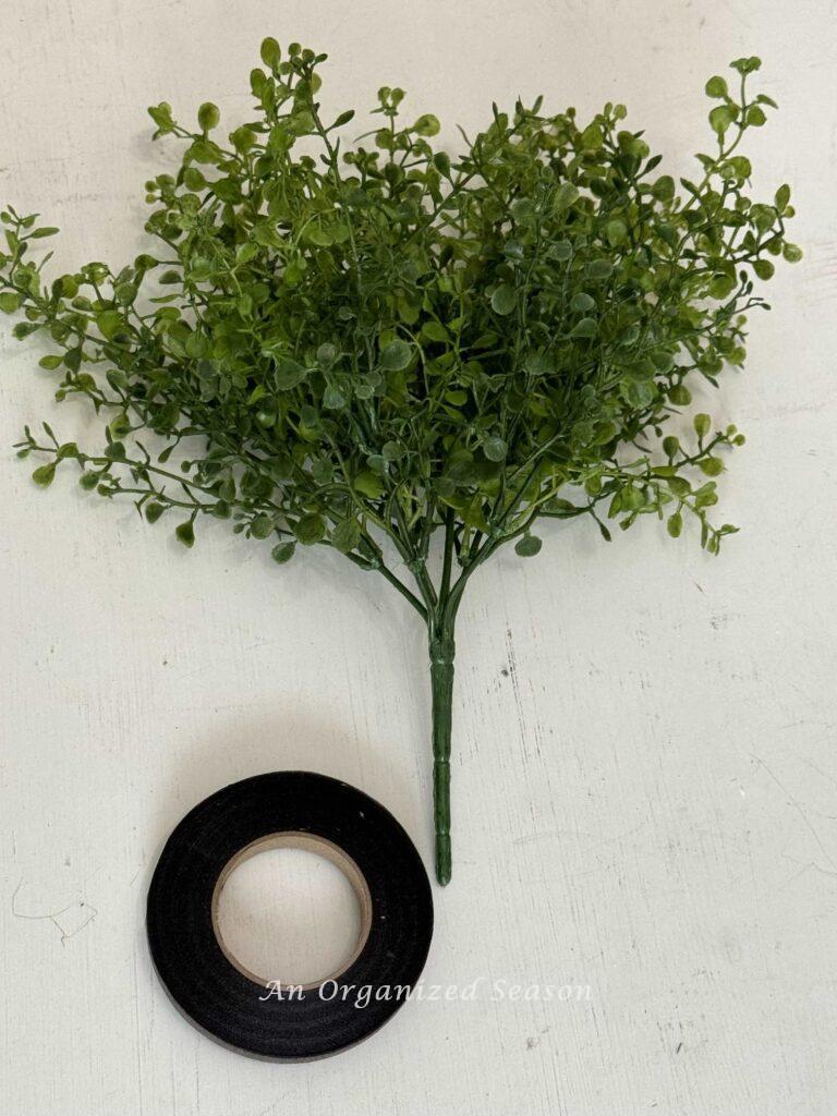 A greenery pick and roll of brown floral tape. 