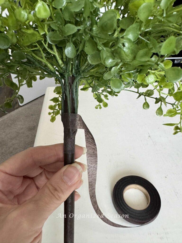 Someone wrapping floral tape around stems. 