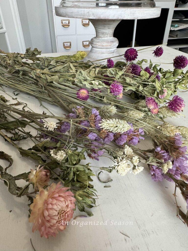 Step two to make a dried flower arrangement is to separate the like flowers into groups. 