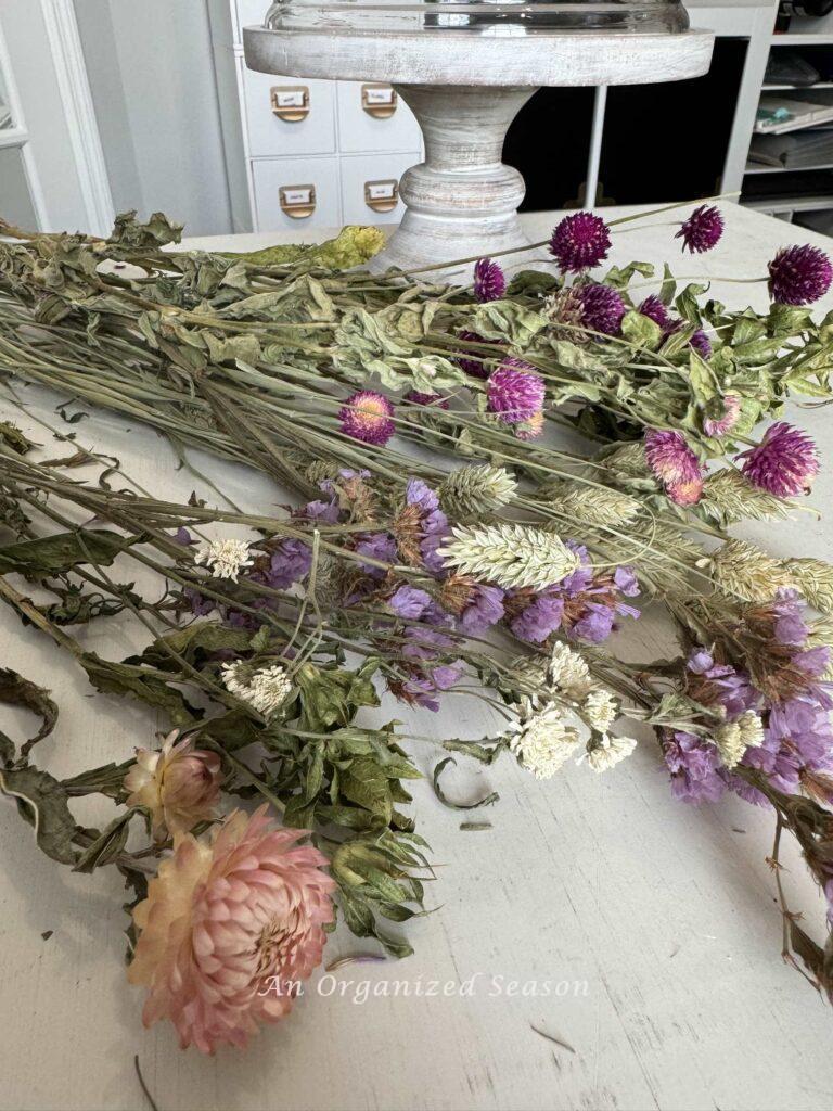 Step two to make a dried flower arrangement is to separate the like flowers into groups.