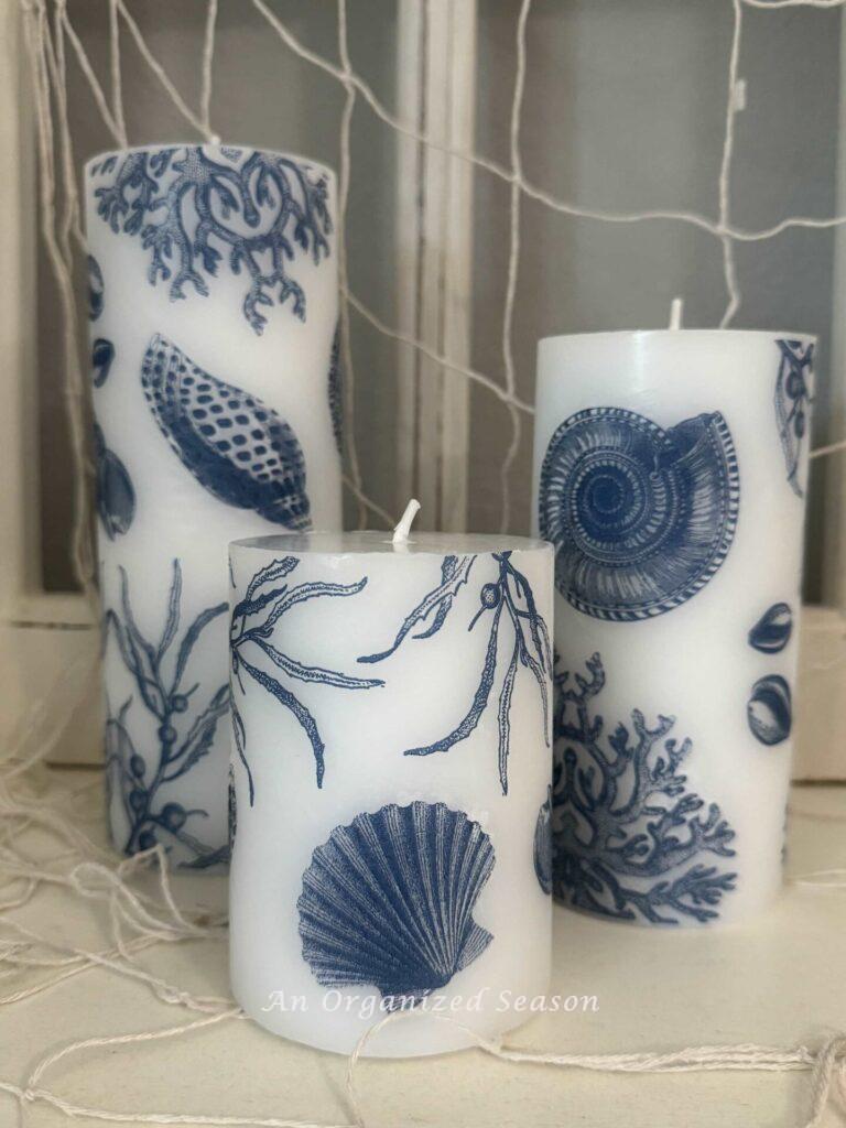 Three coastal-inspired candles with blue shell design. 