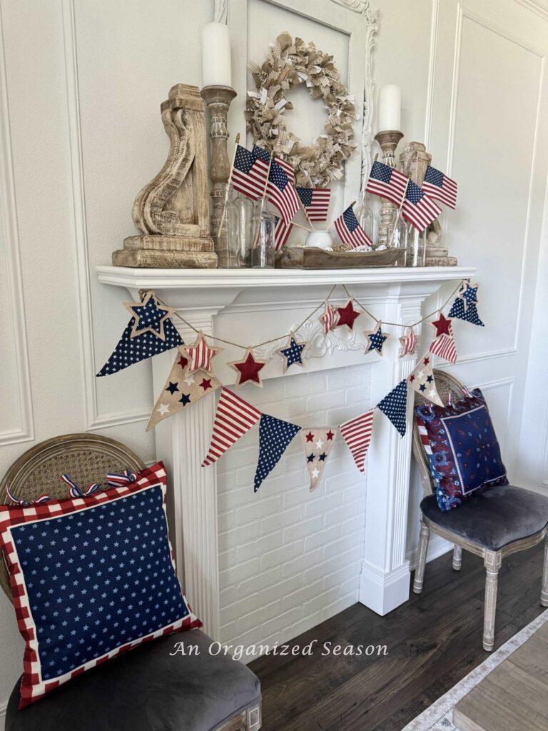 Fireplace decorated with patriotic items with two chairs on either side holding patriotic pillows. 