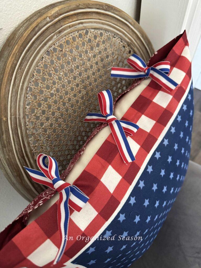 Pillow cover tied with red, white, and blue ribbon tied into bows. 