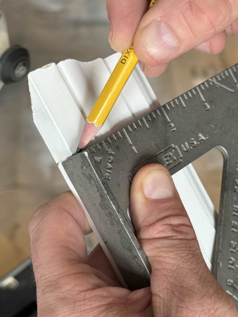 A man marking a trim piece with a pencil and ruler. 
