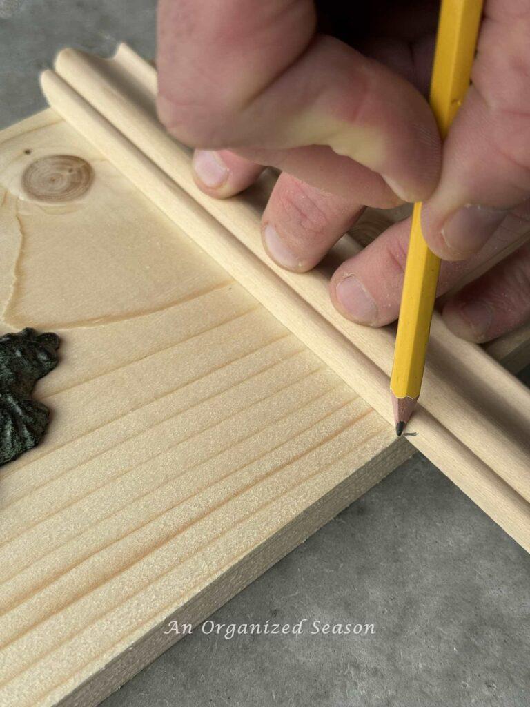 A man making a pencil mark on a piece of wood. 
