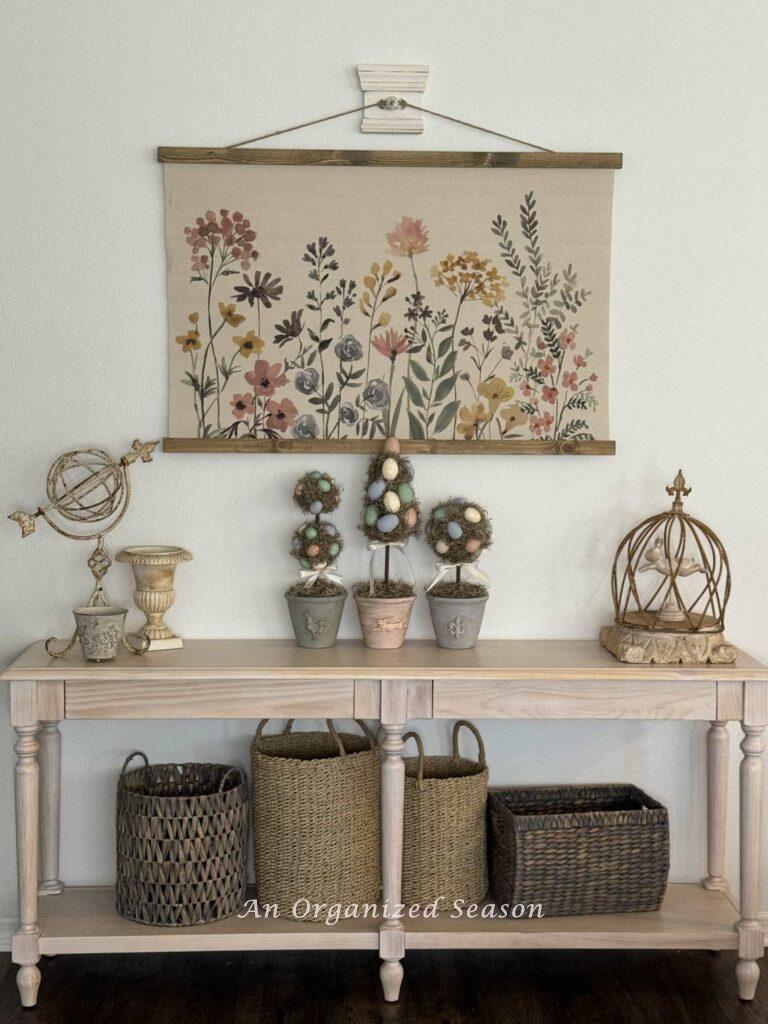 A DIY wall hook holding a floral canvas over a decorated console table. 