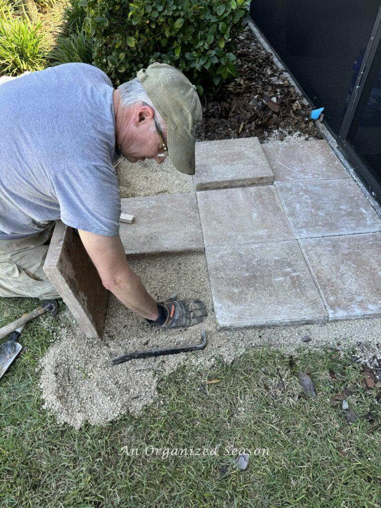 A man  showing DIY lawn care by installing outdoor pavers. 