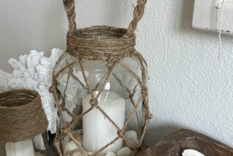A coastal lantern, glass candle holder, and a piece of white coral.