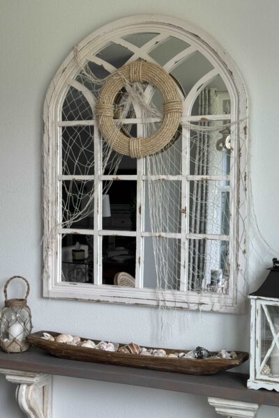 A coastal DIY rope wreath hanging on a mirror draped with a fishing net.