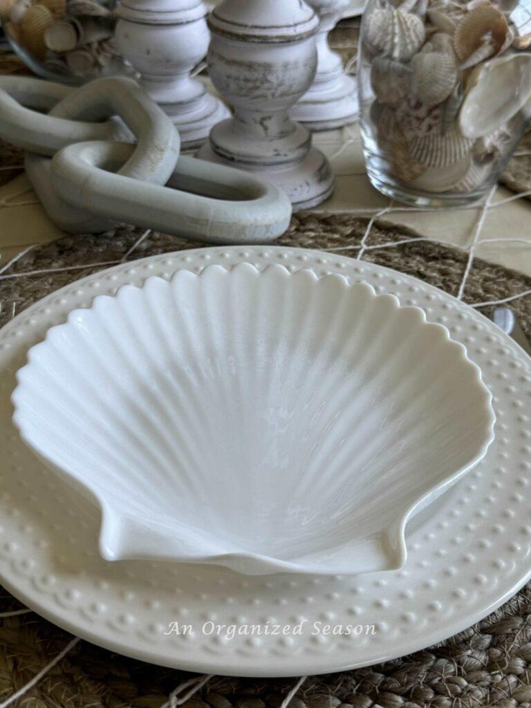 A white shell plate on top of a white dotted dinner plate is perfect for coastal table decor.