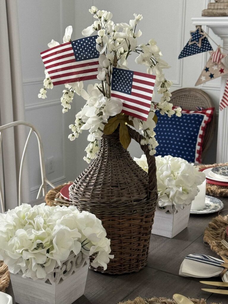A demijohn with white flowers and two American flags. 