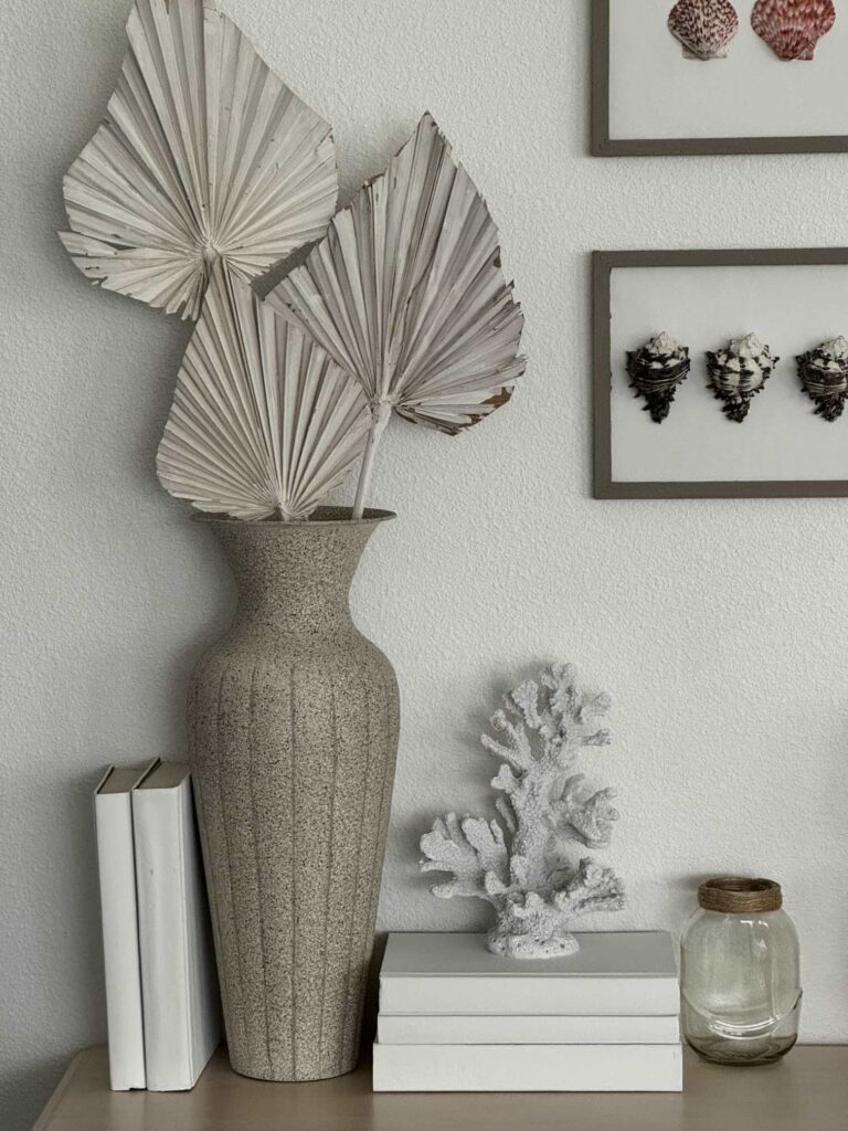 Three white palm branches in a vase and a coral figurine on top of three books make perfect summer home decor. 