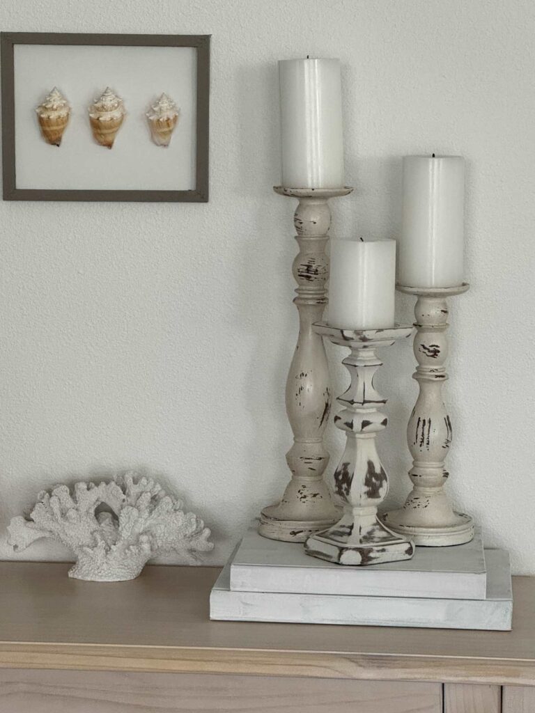 Three white candlesticks with white pillar candles.  