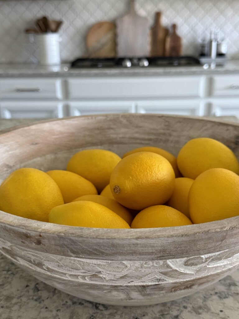 A wooden bowl full of lemons. 