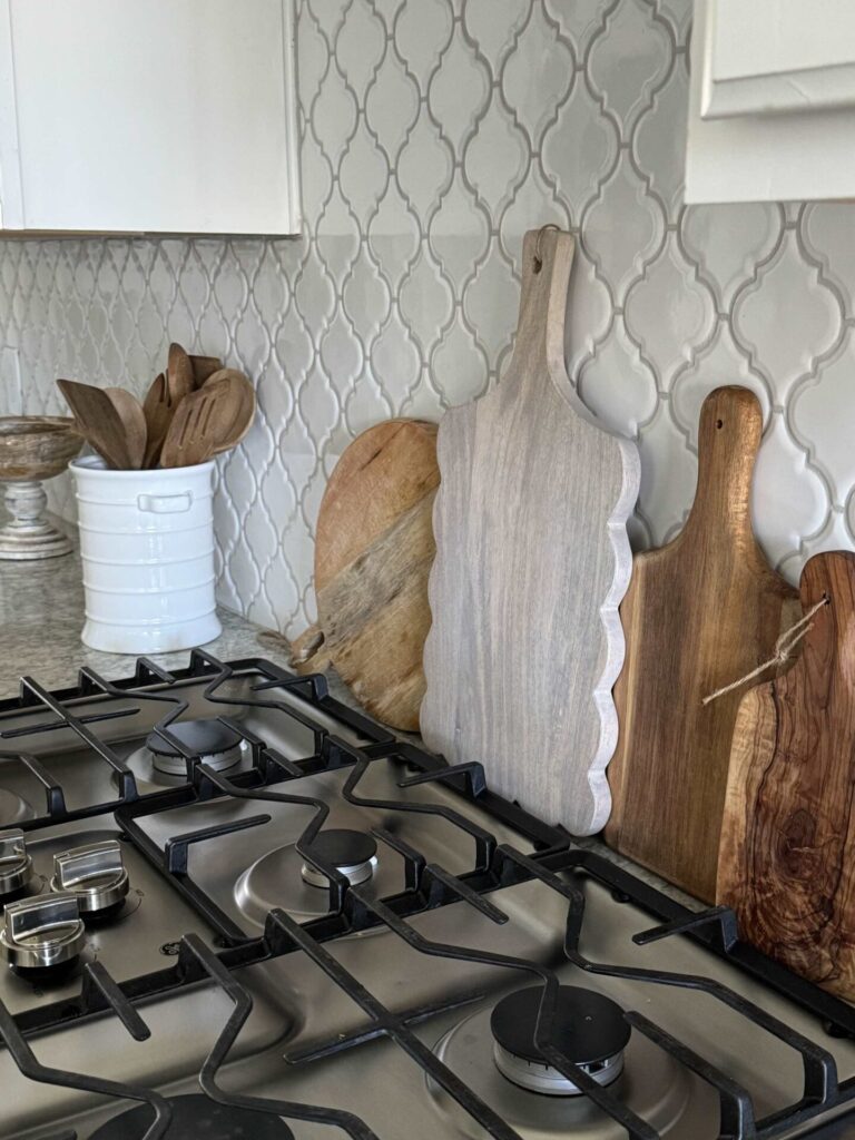 Four wood cutting boards behind a stove. 