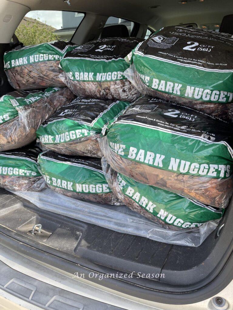 Bags of mulch in the back of an SUV that will be used for DIY lawn care. .
