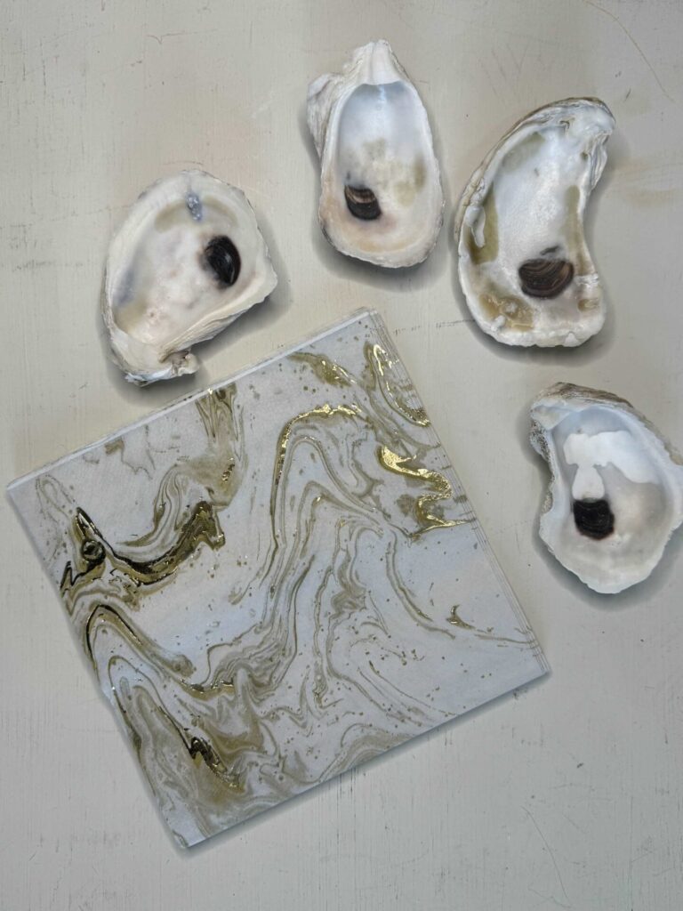 Four oyster shells and gold and white swirled paper napkins. 