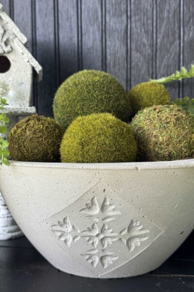 A DIY concrete bowl filled with moss balls.