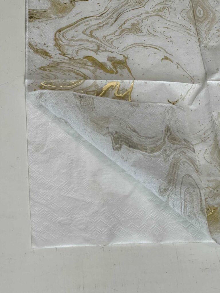 A gold and white swirled napkin with the top layer peeled back. 