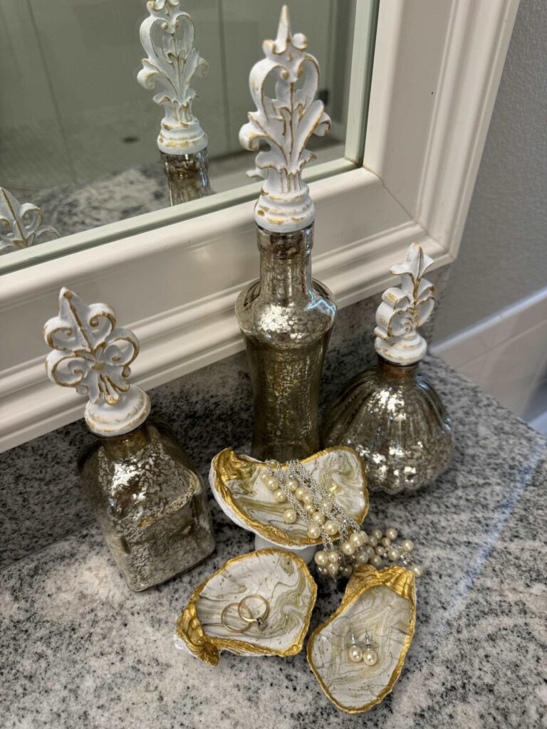 Three decorative bottles with oyster shell trinket dishes in front of them.