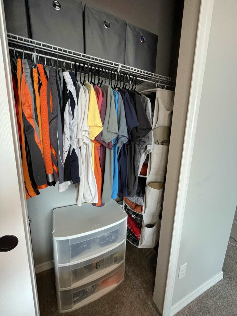 An organized clothes closet with plastic shelves on the floor. 