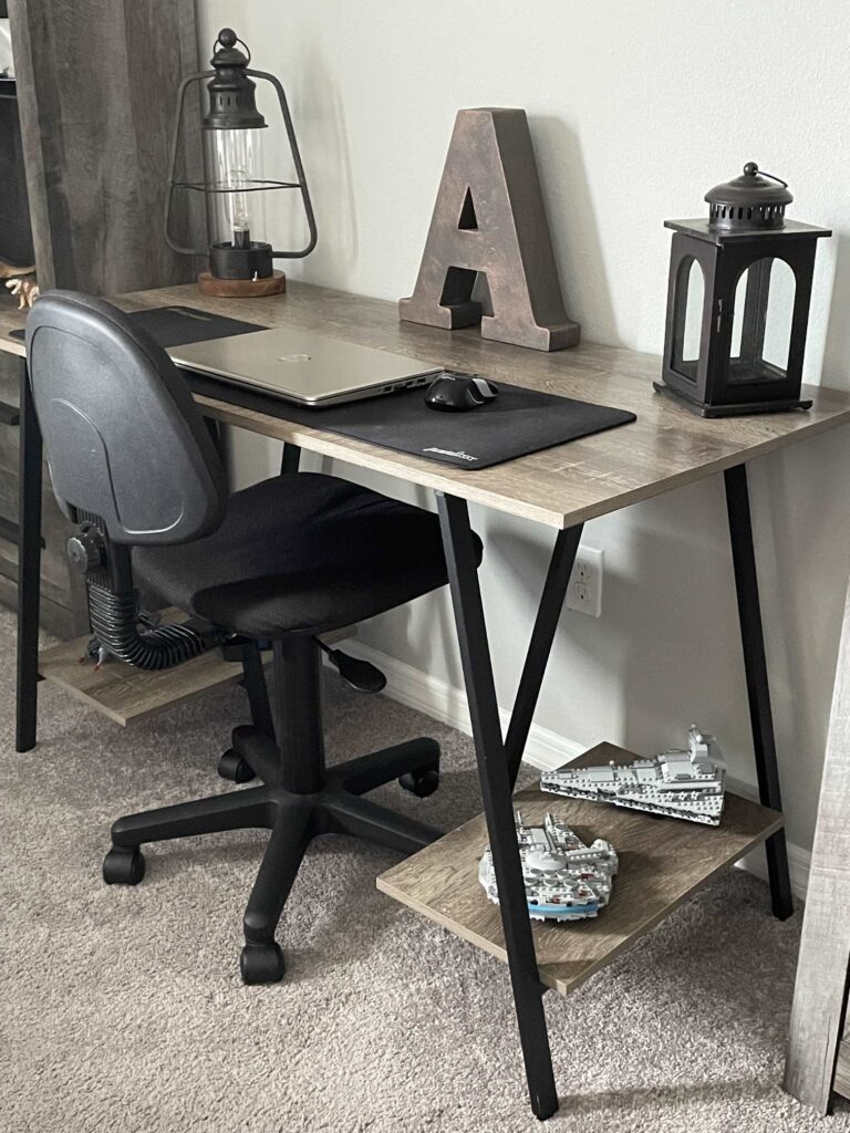 A desk and chair holding two lanterns, laptop, and a decorative letter "A" ready for back to school homework. 